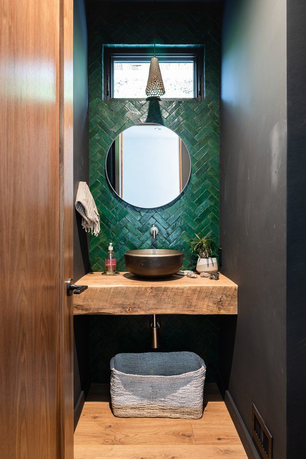 a bathroom with a sink, mirror and green tile on the wall above it's counter