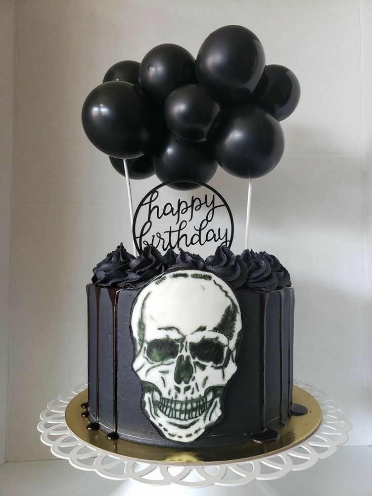 a birthday cake decorated with black balloons and a skull