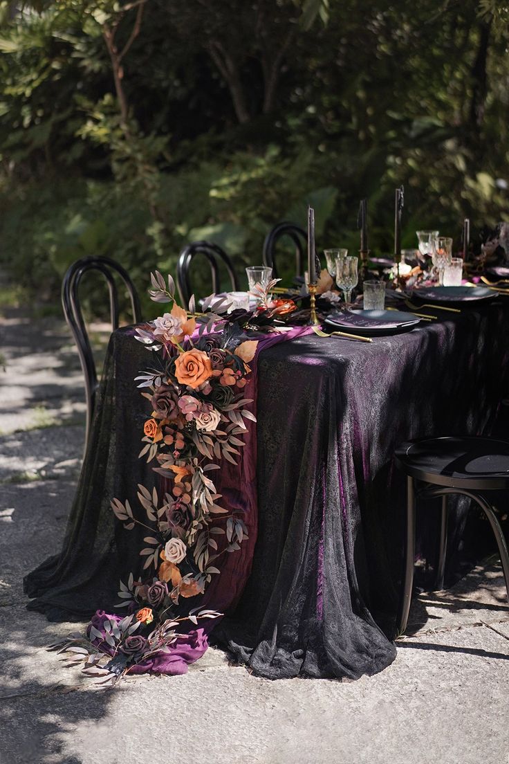 the table is set with black cloths and flowers on it, along with candles