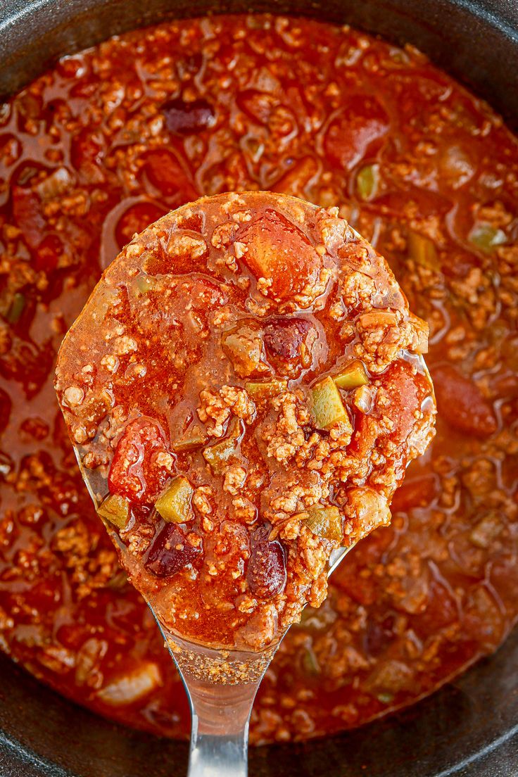 a spoon full of chili and beans in a pot