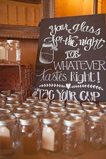 a table topped with lots of mason jars filled with water and candles next to a sign that reads, your glass is for the night