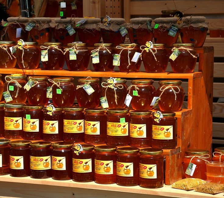 many jars of honey are on display in a store shelf with tags attached to them