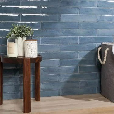 a blue brick wall next to a wooden table with two vases on it and a rope