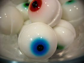 several white balls with blue and red eyes in a bowl filled with water or liquid