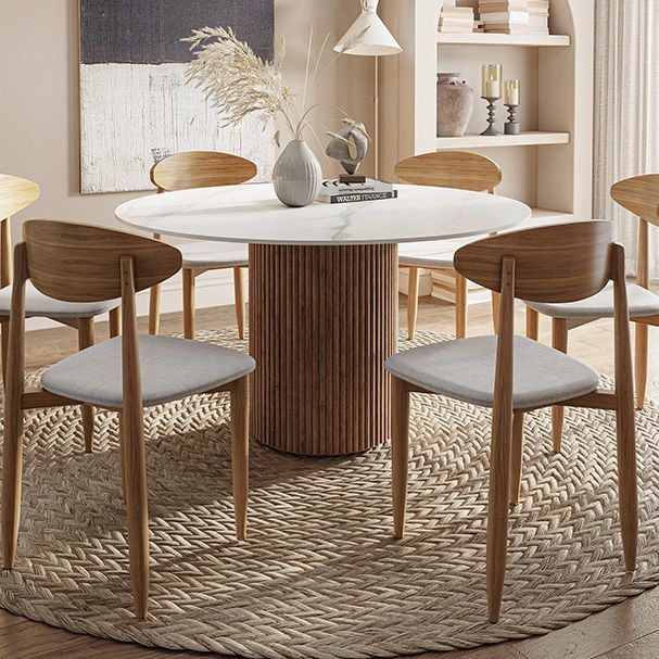 a round table with four chairs around it in a room that has beige walls and wooden floors