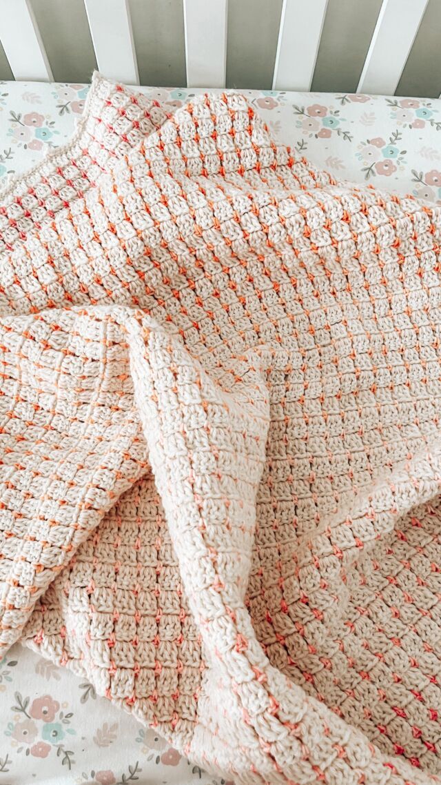 an orange and white blanket on top of a crib