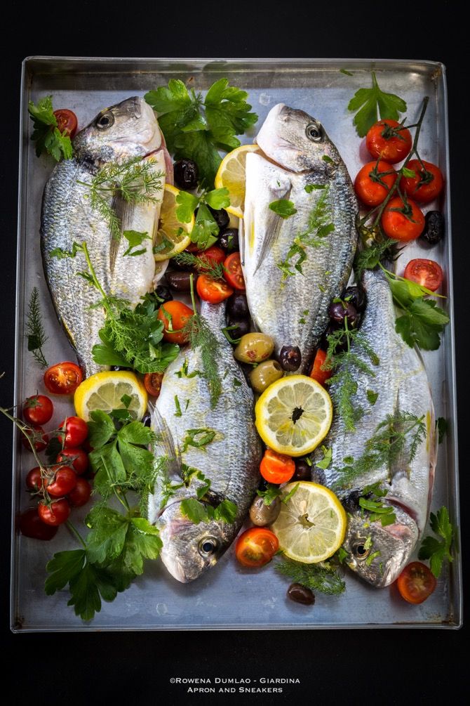 fresh fish with lemons, tomatoes, olives and parsley