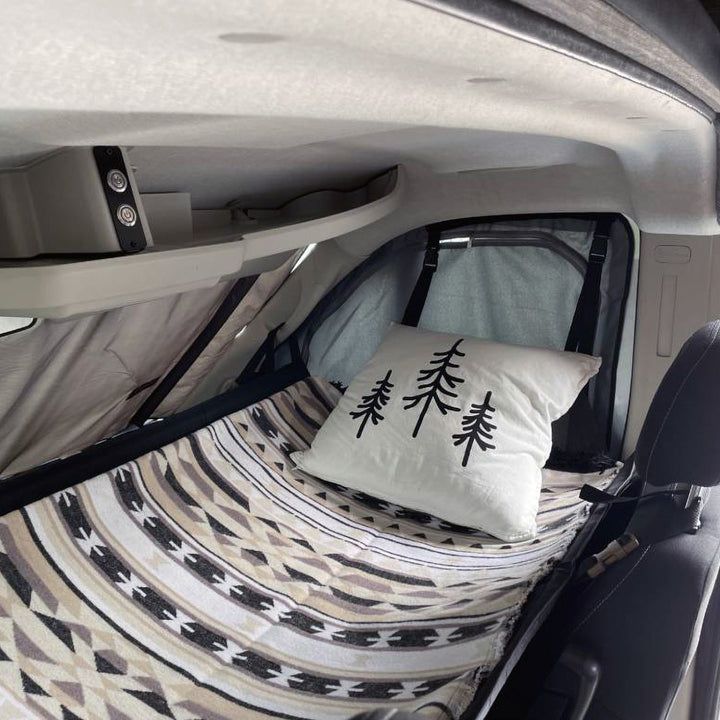 the interior of a vehicle with a bed and pillows on it's back end