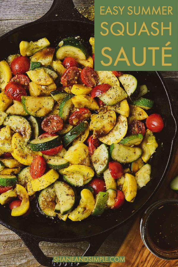 a skillet filled with grilled zucchini, tomatoes and peppers on top of a wooden table