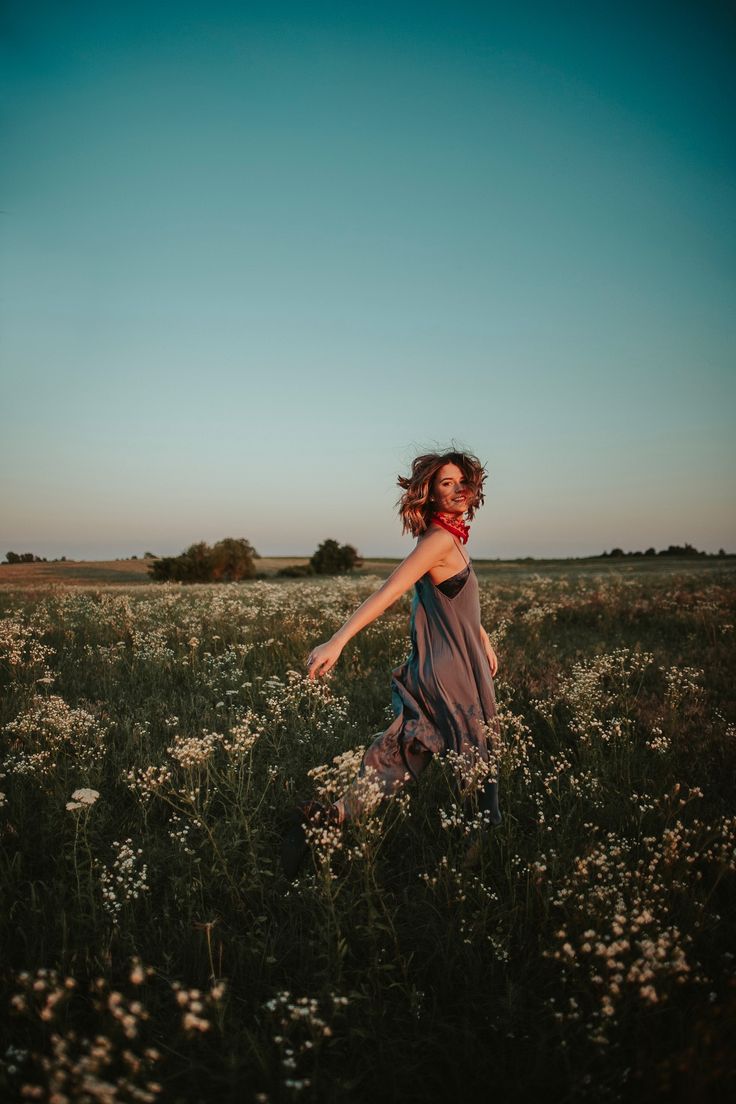 a woman walking through a field with wildflowers