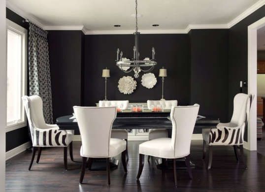 a black and white dining room with zebra print chairs, chandelier and table