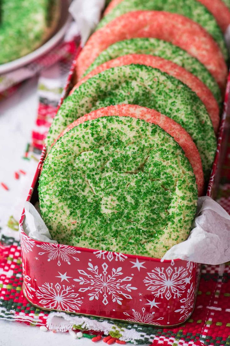 green sprinkle cookies in a red box on top of a christmas table cloth