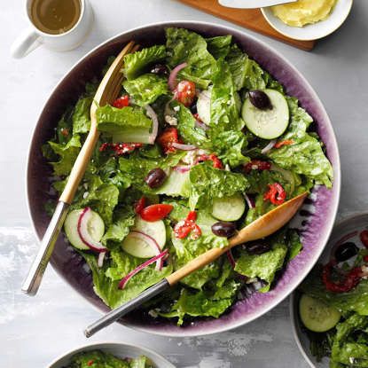 two bowls filled with salad on top of a table next to plates and utensils