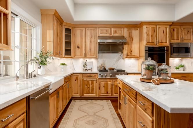 a large kitchen with wooden cabinets and white counter tops, along with an area rug on the floor