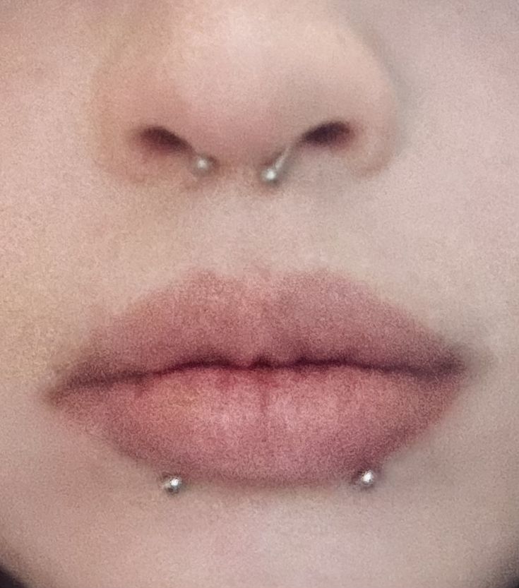 a woman's nose with two piercings on her left side and the middle part of her lip