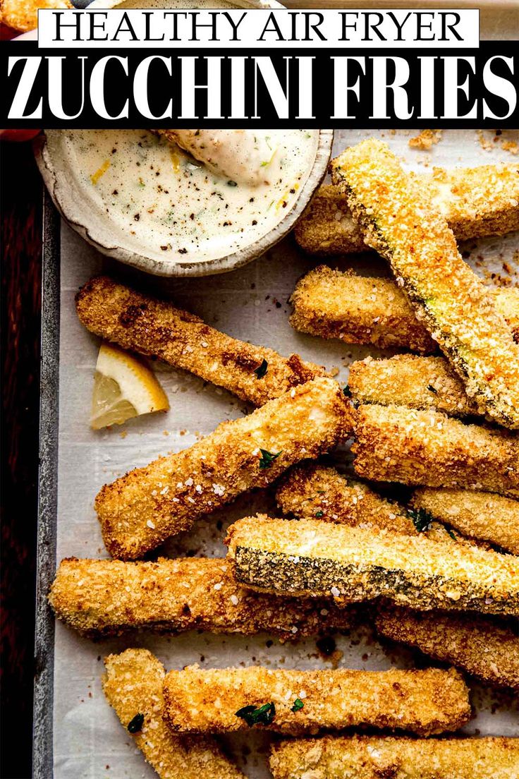 some fried food is on a tray with dipping sauce and lemon wedges next to it