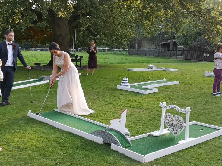 a bride and groom playing miniature golf in the park