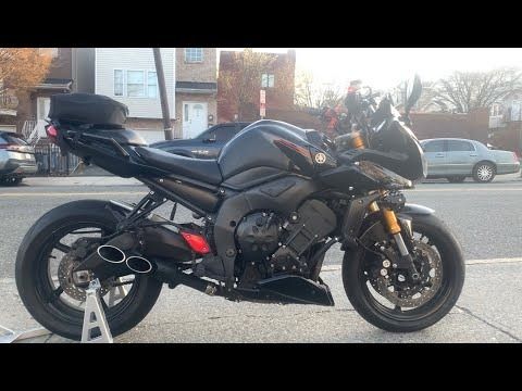 the motorcycle is parked on the side of the road in front of some cars and buildings