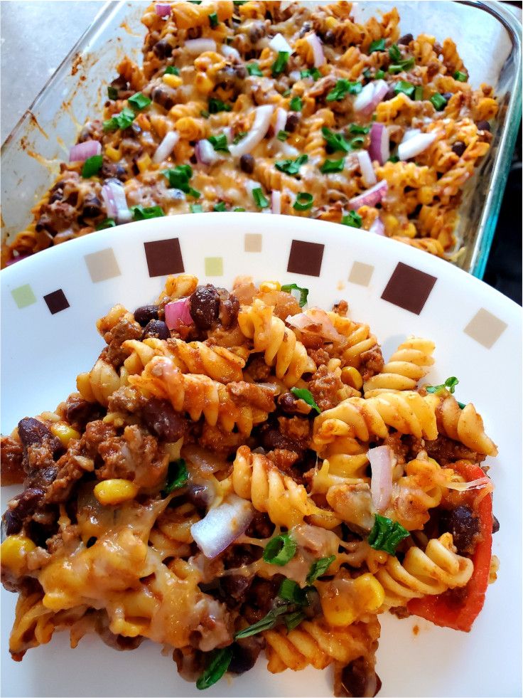 two plates filled with pasta and meat covered in sauce, onions, green onions and parmesan cheese