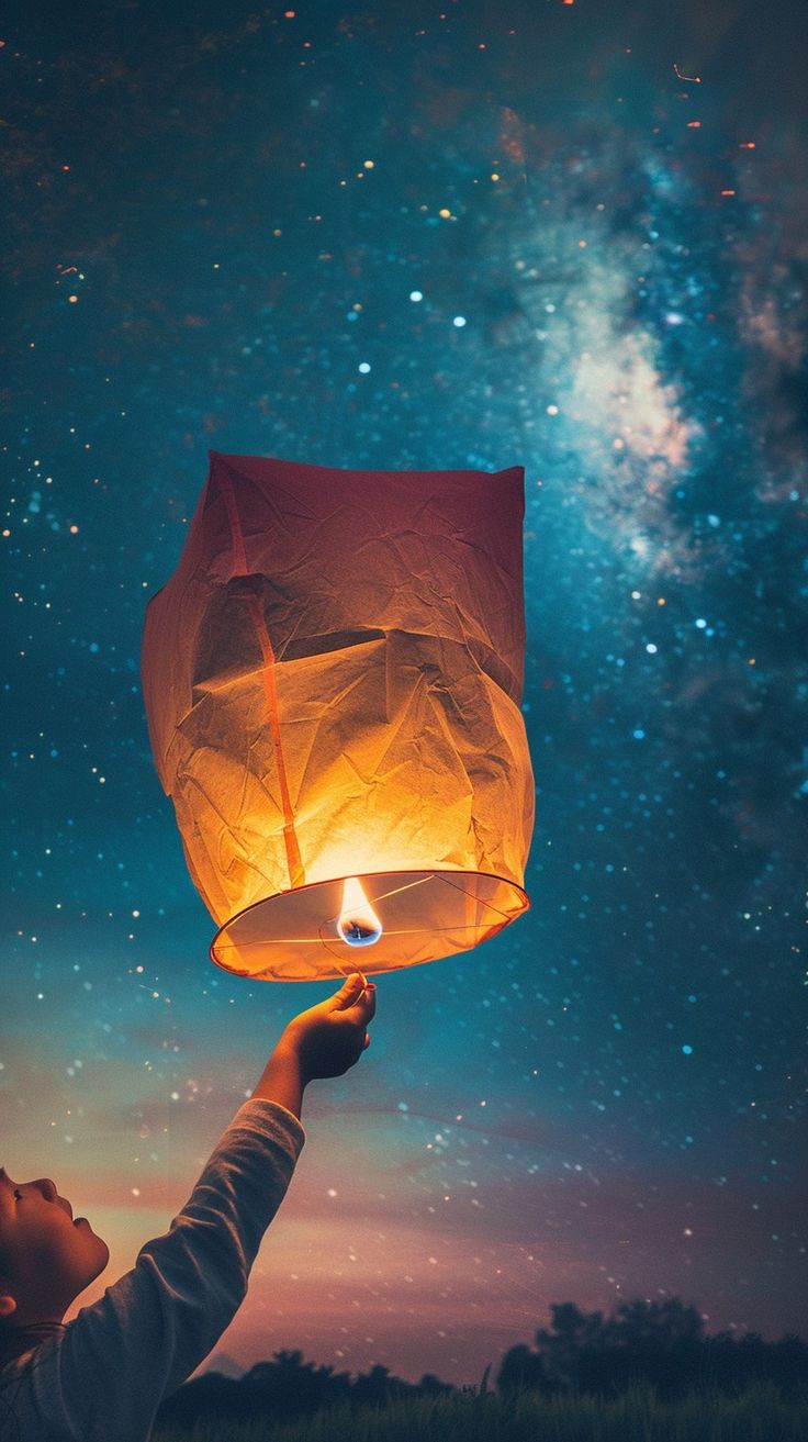 a person holding up a paper lantern in the sky