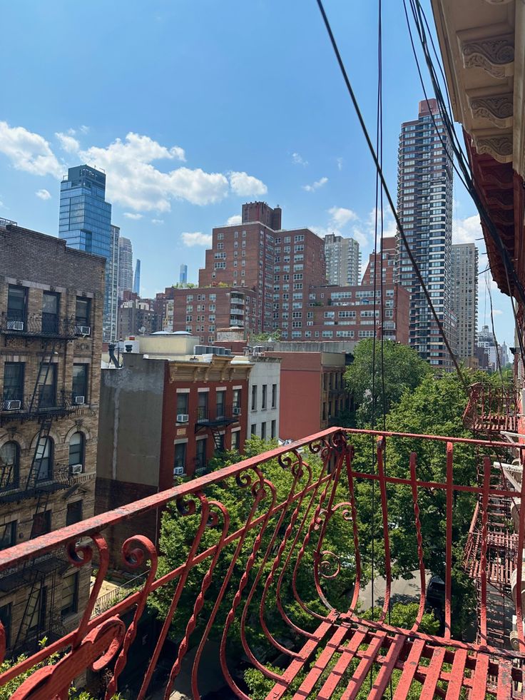 a balcony with red railings and city buildings in the backgroung area