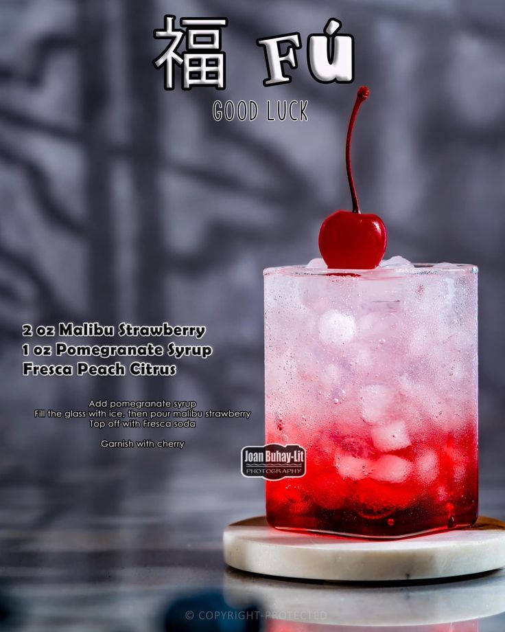 a red drink with a cherry on the top is sitting on a table in front of an advertisement