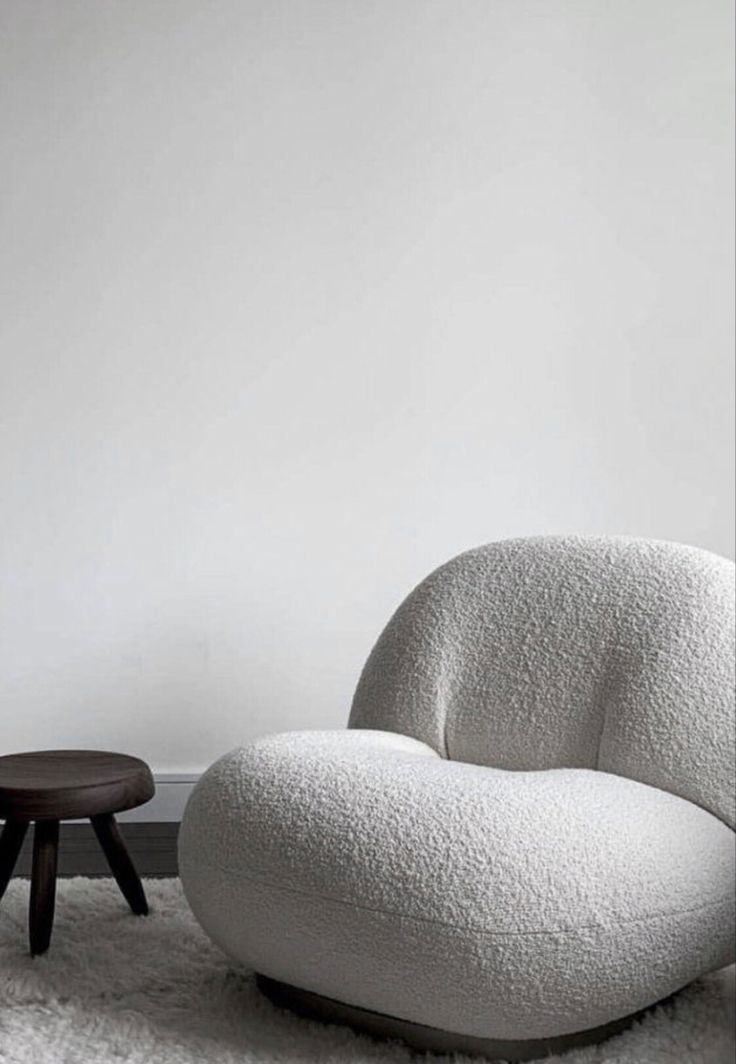 a white chair sitting on top of a shaggy rug next to a wooden foot stool