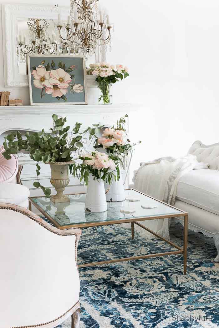 a living room filled with furniture and flowers on top of a glass topped coffee table