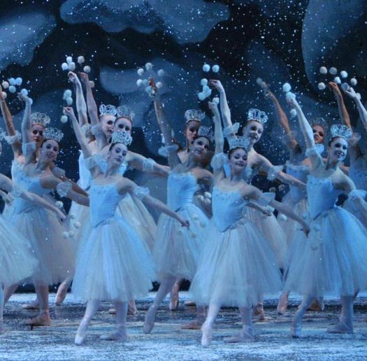 a group of ballerinas in white tutus with their arms up and hands raised