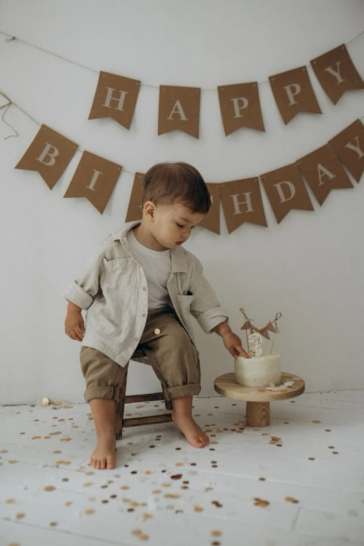 a little boy sitting on a chair with a birthday cake