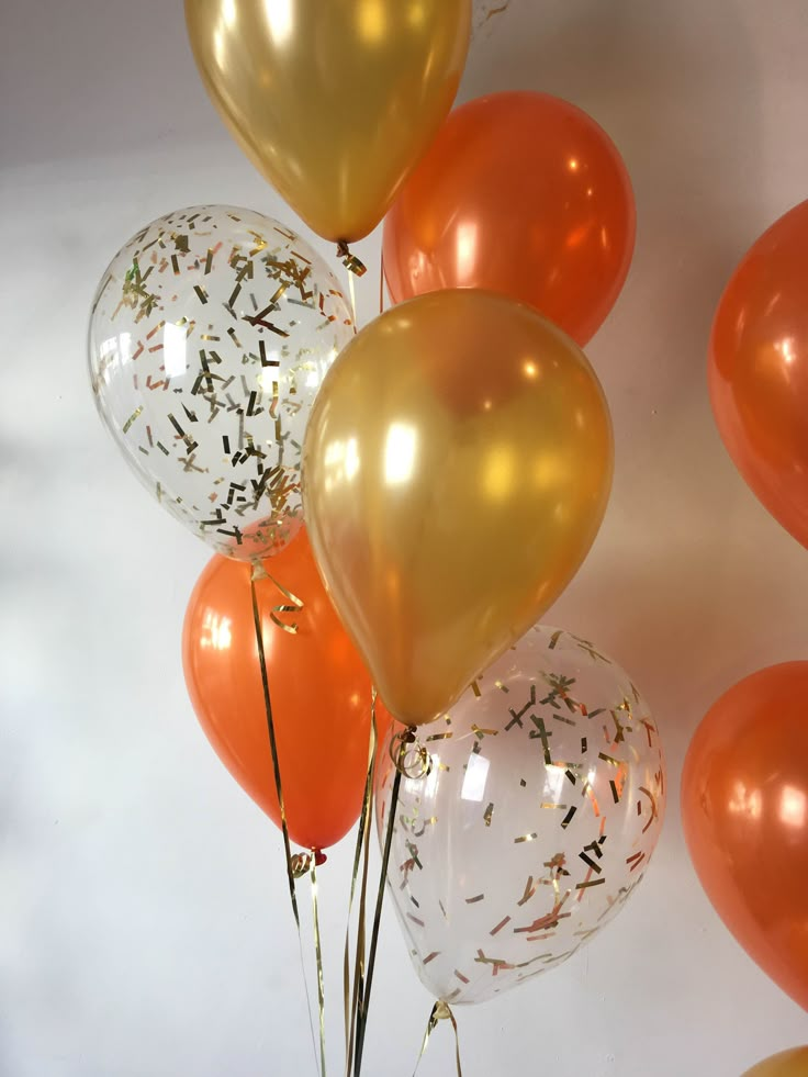 orange and white balloons with confetti on them are arranged in a vertical arrangement