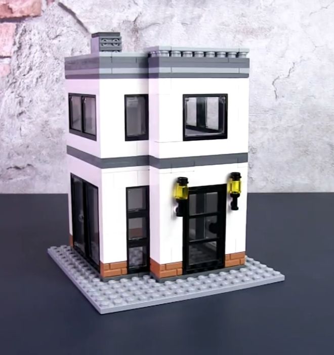 a small white building sitting on top of a black table next to a brick wall