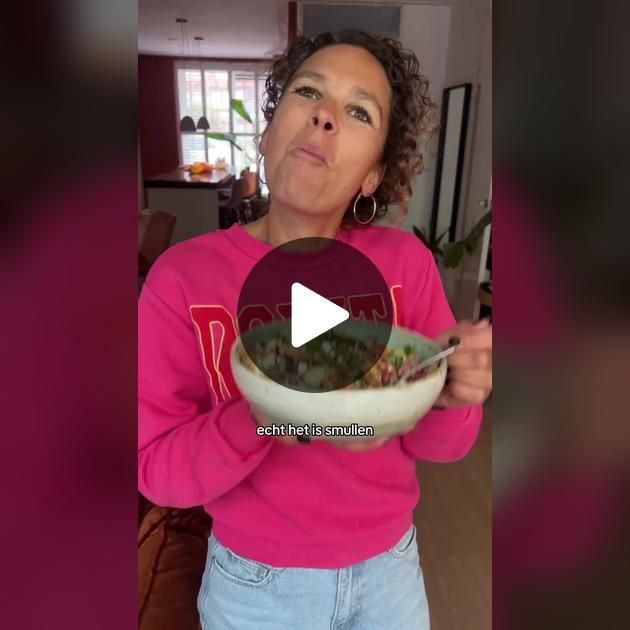 a woman in pink shirt holding a bowl with food inside of her hands and looking up at the sky