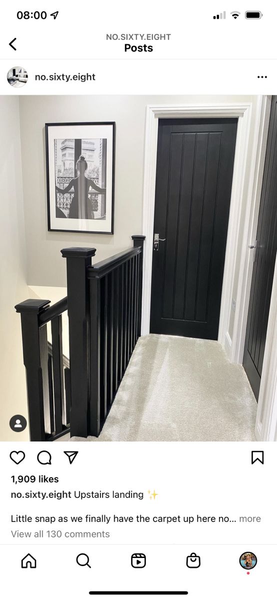 a black door and some stairs in a room with pictures on the wall above it