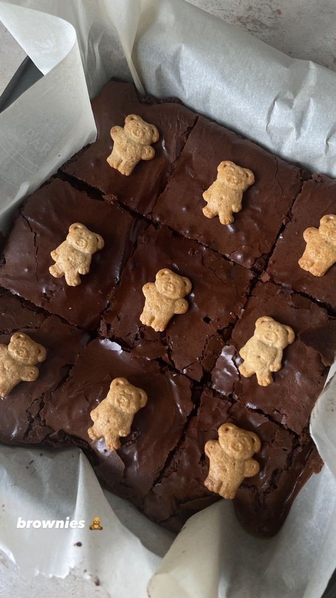 there are many brownies with teddy bears on them in the paper wrapper and one is cut into squares