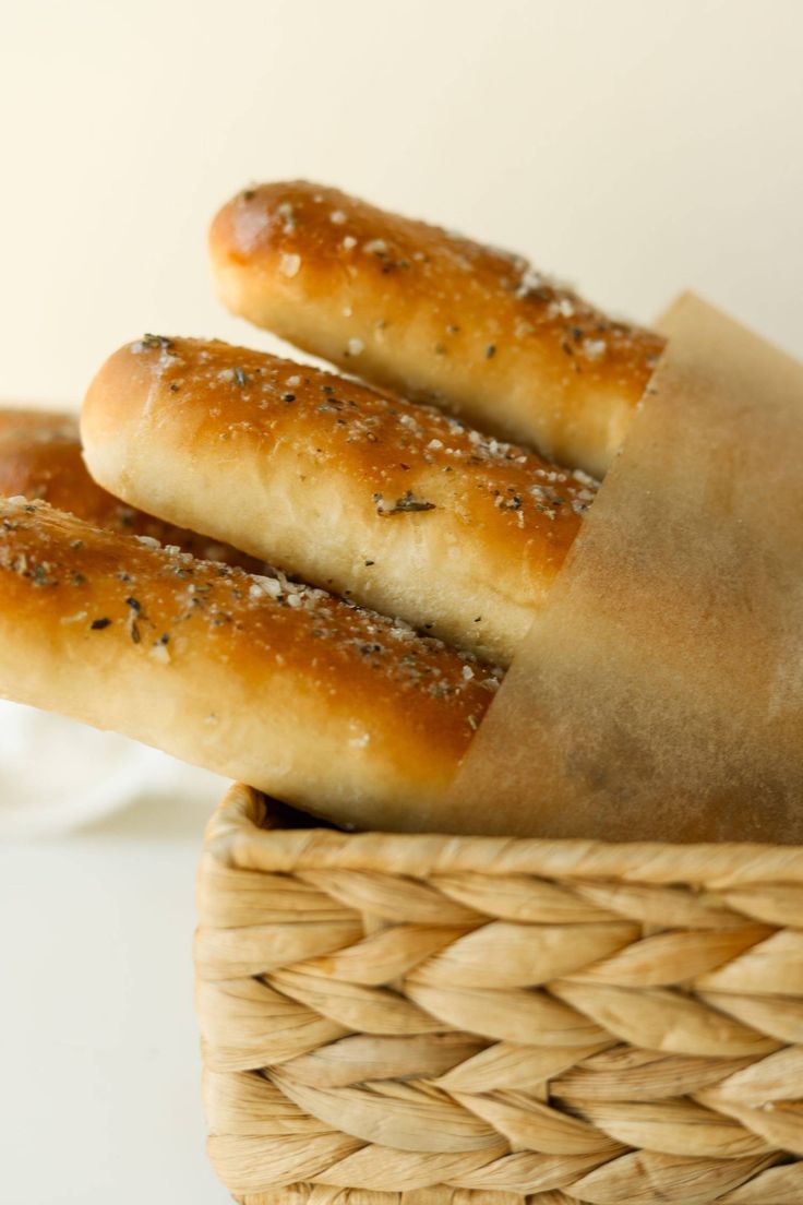 three breadsticks in a basket on a table