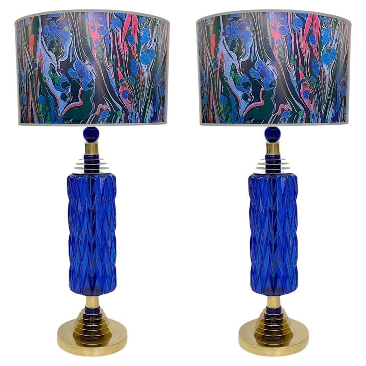 two lamps with blue and pink designs on them, one is turned on the other side