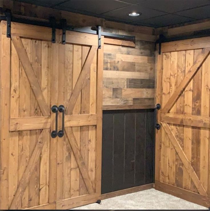 the inside of a horse barn with wooden doors and black hardware on each side of the door