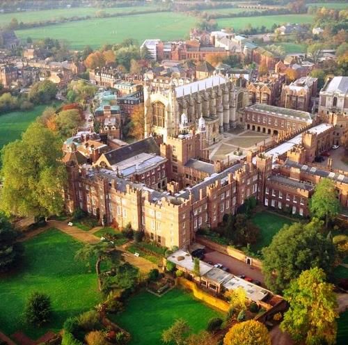 an aerial view of a large building in the middle of a green field with trees