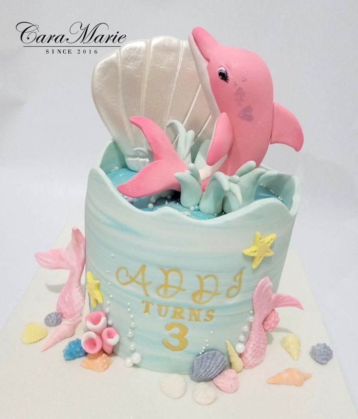 there is a cake that looks like a dolphin in the ocean with shells and seashells on it