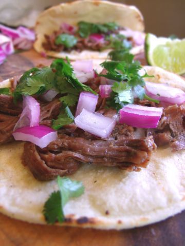 three tacos with meat, onions and cilantro