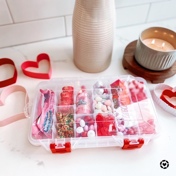 a plastic container filled with lots of different types of candies next to a candle