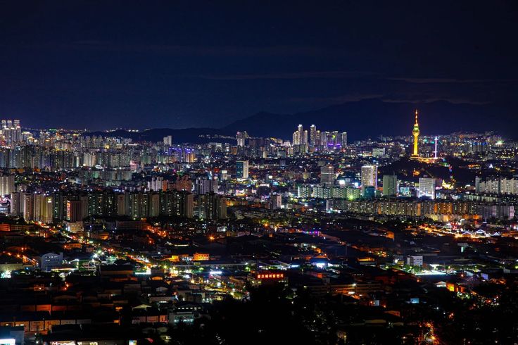 an aerial view of a city at night with lights on and skyscrapers in the background