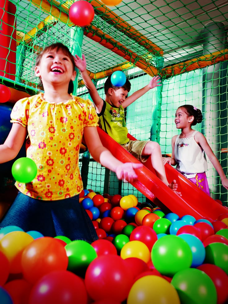 children playing in an indoor play area with colorful balls