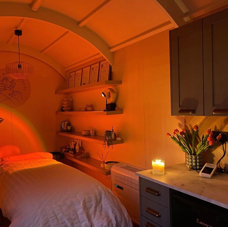 a bed sitting in a bedroom next to a counter top under a light that is on