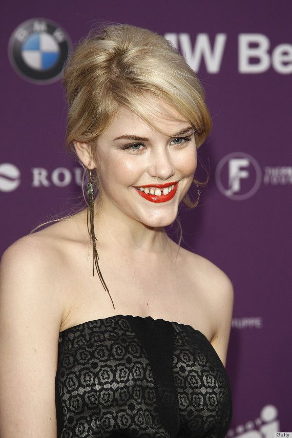 a woman with bright red lipstick on her face and black strapless dress smiling at the camera