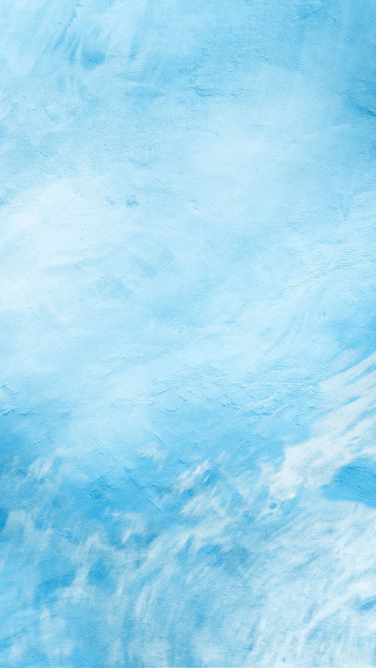 a man riding a snowboard down the side of a snow covered ski slope in front of a blue sky