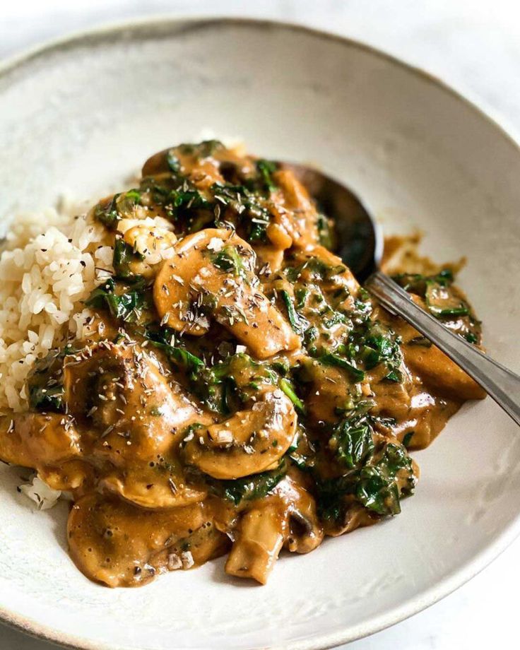 a white plate topped with rice and meat covered in sauce