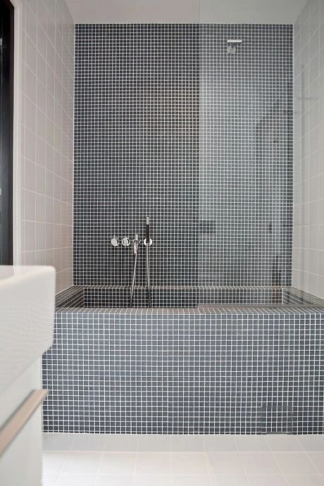 a bathroom with white tile and gray tiles on the walls, along with a bathtub