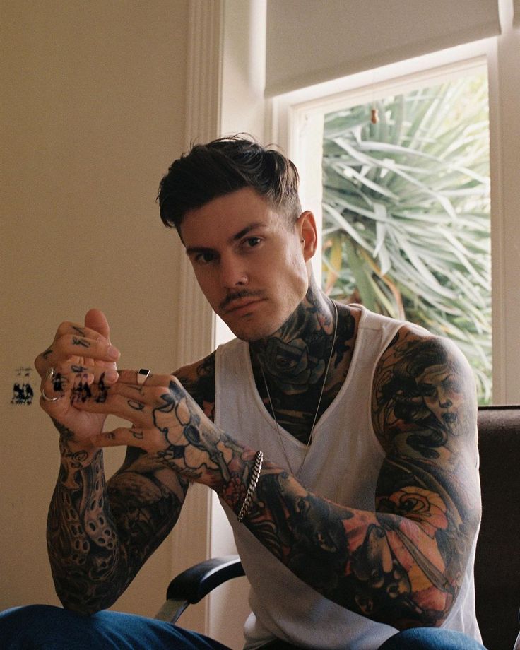 a man with tattoos sitting in a chair